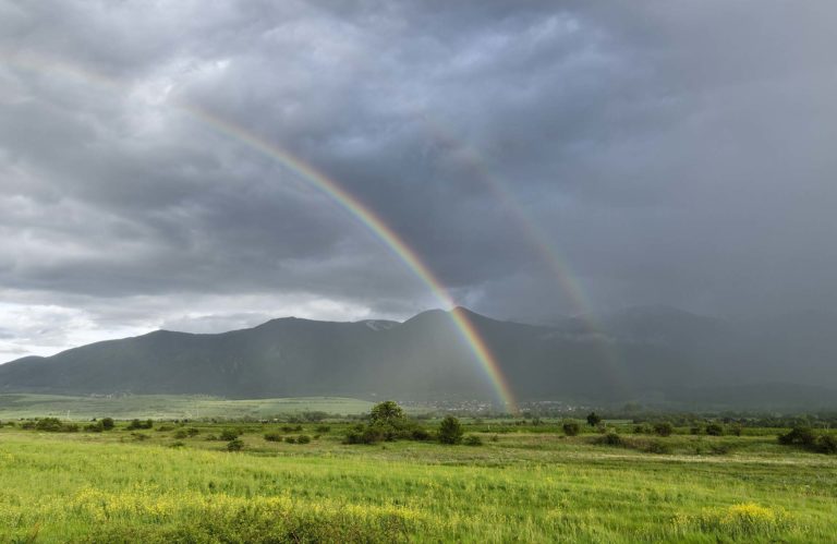 Double rainbow over field and mountain Bulgaria